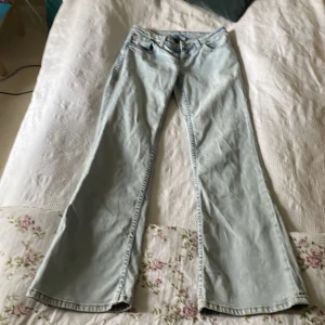 Ljusblå bootcut jeans H&M Divided 36 - Säljer ett par ljusblå bootcut jeans från H&M Divided i storlek 36. Jeansen har klassisk femficksmodell, snygga kontrastsömmar och broderad detalj på bakfickan. Tillverkade i mjuk bomullsdenim med en riktigt skön passform.