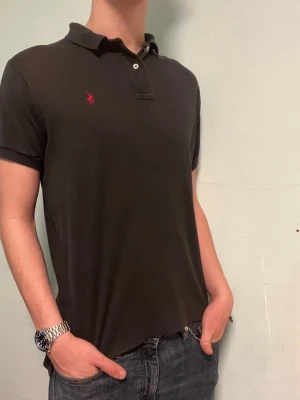 Ralph Lauren piké svart - Säljer denna stilrena svarta pikén från Ralph Lauren. Pikén är i bra skick, förutom att den är lite nopprig. Storlek M. Har du några frågor? Tveka inte att höra av dig😊Allt gott Deluxe garderoben