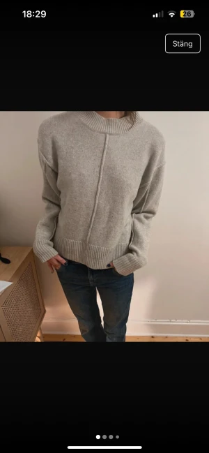 Grå stickad tröja med ribbad kant ull - Säljer en grå stickad tröja med bred ribbad kant vid hals, ärmslut och nederkant. Tröjan har en snygg söm framtill och är lite oversized med långa ärmar. Perfekt för dig som gillar enkel och chill stil.