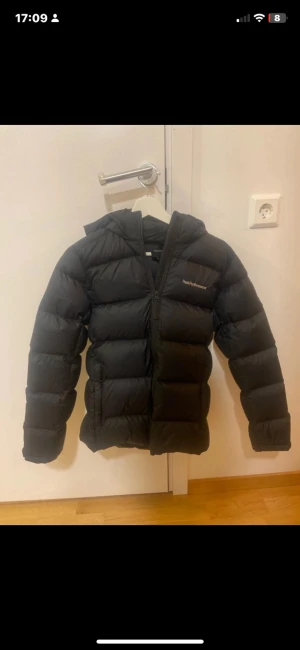 Marinblå dunjacka Peak Performance 160 - Säljer en svart dunjacka från Peak Performance i storlek 160. Jackan är fluffig och har huva, dragkedja och fickor. Perfekt för vinter och kallt väder. Har köpt från Länna sport då den kostade mig 2500kr men den passade inte som önskan så den är knappt använd och den är i unisex. Modellen är ”JD FROST DOWN PUFFER JACK”