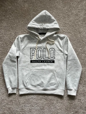 Grå Polo Ralph Lauren hoodie - Säljer denna fräscha hoodien då den var för liten, men i övrigt helt oanvänd. Storlek är L men passar mer som M då den är liten i storleken. Hör gärna av dig vid minsta fråga eller fundering!