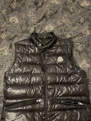 Svart dunväst från Moncler - Svart dunväst från Moncler i nyskick storlek S fast passar till M, använt runt 10 gånger köpte den ny för 7000 för mindre än ett halvår sedan mitt pris 3500 skicka ett bud annars mvh