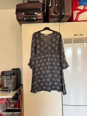 Mönstrad klänning från Odd Molly - Supersnygg mörkgrå klänning från Odd Molly med vitt mönster, v-ringning och vida ärmar. Lätt och luftig modell i bomull, perfekt för dig som gillar boho-stil. Klänningen har en avslappnad passform och är kort i modellen. Från märket Odd Molly. Storlek 3 som enligt deras storleksguide motsvarar en L. Kan vara liten i storlek. Mycket fint skick, jag hittar inga synliga anmärkningar eller defekter. 