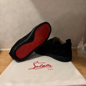 Christian Louboutin mörk blå sneakers mocka - Mörk blåa sneakers från Christian Louboutin i lyxig mocka med klassisk röd sula och diskret logga på sidan. Skorna har rund tå, snörning och en stilren design som passar perfekt till streetwear eller en mer dressad look.