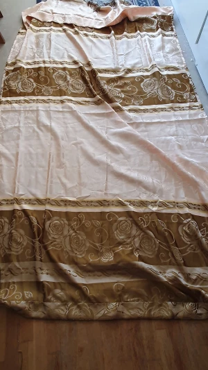 Gardin - Säljer en stor vanlig gardin i beige och brunt med vackert blommönster. Gardinens kanter har en fin fransdetalj som ger en extra touch av stil. Längd: 248 cm och Bredd: 141cm. (Det är en gardin men vet inte vilken slags men den är inte så tunn)