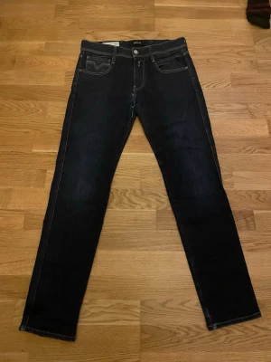 Replay mörkblå jeans straight fit - Snygga mörkblå jeans från Replay med klassisk straight fit och kontrastsömmar. Jeansen har fem fickor, Replay-logga vid fickan och coola detaljer på bakfickorna. Perfekt för dig som gillar stilrena och tidlösa jeans med lite edge.