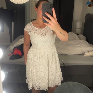 Studentklänning  - Superfin vit kortklänning i spets med blommigt mönster och öppen rygg. Perfekt till studenten! Endast använd en dag