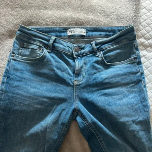 Blå bootcut jeans från Zara, stl 38 - Snygga blå jeans från Zara i klassisk bootcut-modell. Jeansen har fem fickor, normal passform och är tillverkade i mjukt bomullstyg med lite stretch. Perfekta för dig som gillar en tidlös look med lite utsvängda ben.