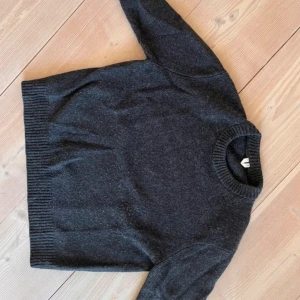 Mörkgrå stickad tröja från Arket - Mysig mörkgrå stickad tröja från Arket i storlek S. Tröjan har en klassisk rund halsringning och ribbade muddar vid ärmslut och nederkant. Perfekt för lager-på-lager under kyliga dagar och enkel att matcha med. Hör av er vid minsta lilla fundering😁
