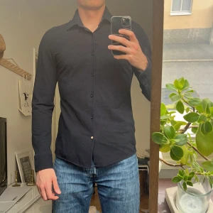 Hugo BOSS - Stilren svart skjorta från BOSS i slim fit-modell. Skjortan har klassisk krage, långa ärmar och knappar framtill. 