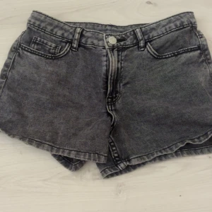 Grå jeansshorts  - Snygga grå jeansshorts med hög midja och klassisk femficksdesign. De har råa kanter nedtill för en cool vibe och tydliga sömmar som ger extra edge. Perfekta för sommaren och passar till allt från sneakers till boots.
