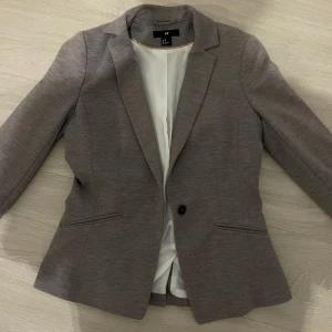 Grå kavaj från H&M, storlek 38 - Snygg grå kavaj från H&M i storlek 38. Skulle säga att den passar även XS och S fast lite ”oversized”. Fodrad med ljus insida och har slits bak 🌸