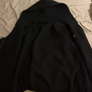 Svart hoodie från Polo Ralph Lauren - Svart hoodie från Polo Ralph Lauren med röd broderad logga på bröstet. Köpt från en kompis sedan innan och både etiketten och tvättlappen är borttagen, men överlag är tröjan äkta då min kompis köpte den för ungefär 2000kr. Storleken  är M och överlag är den bekväm och en riktig skön tröja för uppkommande höst. Min kompis har inte överanvänt den, så den är i ett mycket bra skick. 