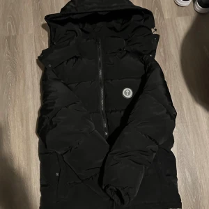Svart pufferjacka från Trapstar - Säljer en svart pufferjacka från Trapstar med huva och dragkedja framtill. Jackan har en clean look med Trapstar-logga på bröstet och är perfekt för kalla dagar. Fylld för extra värme och har en modern, oversized passform. Om det behövs kan vi skicka på baksidan av jackan det står Trapstar på baksidan av jackan. Ni får pruta om ni vill 