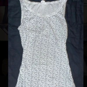 Vit leopardmönstrad linnetopp - Säljer en vit linnetopp med massor av små hjärnor på. Spetsdetaljninh längs urringningen. Dm om du har frågor ❤️