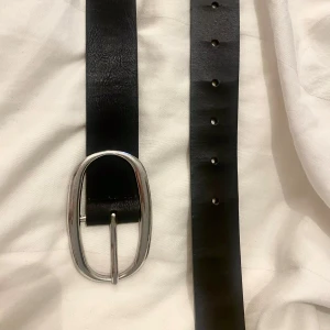 Svart skärp med ovalt silverspänne - Snyggt stilrent skärp från Stradivarius, finns väldigt litet täcken på användning annars i mycket bra och sparsamt skick!