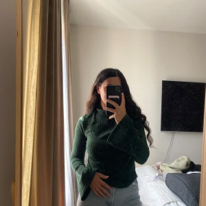 Grön polotröja med utsvängda ärmar - Mörkgrön polotröja från SHEIN i stickad material. Tröjan har långärmade och utsvängda ärmar som ger en cool vibe. Ribbad struktur och figurnära passform. Perfekt att styla med jeans eller kjol för en trendig look.