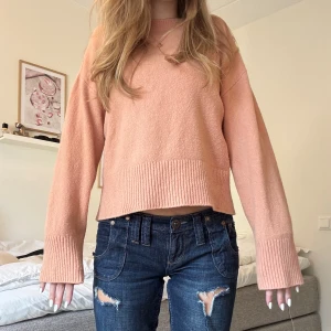 Persikofärgad stickad tröja & Other Stories - Superfin persikofärgad stickad tröja från & Other Stories, Paris Atelier. Modellen är loose fit med breda ribbade muddar och rund hals. Perfekt till jeans och har långa ärmar för en chill vibe. Materialet är mjukt och känns lyxigt.