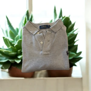 Grå pikétröja från Polo Ralph Lauren - grå pikétröja från Polo Ralph Lauren.jätte bra kondition och fräsch. Storlek S men passar rätt så fint på M också 