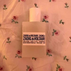 Zadig & Voltaire This Is Her! 30ml - Säljer en Zadig & Voltaire This Is Her! Eau de Parfum, 30 ml. Flaskan är vit och har en stilren, fyrkantig design med svart text på etiketten. Perfekt storlek för att ta med i väskan och passar dig som gillar moderna och eleganta dofter.