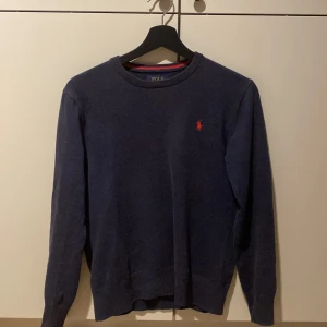 Mörkblå tröja från Polo Ralph Lauren - Säljer en stilren mörkblå tröja från Polo Ralph Lauren i mjuk pima bomull. Tröjan har en klassisk design med långärmad passform och det ikoniska röda broderade logotypen på tröjan. Tröjan är i ny skick och köptes för 1 år sen på mellan dags rean för 869kr. Men började använda den i sommras och säljer nu på grund av att den är för liten.. Tröjan är i storlek 14-16 år/L barnstorlek men skulle säga att den passar runt 150/M. Hör av er om ni har några frågor eller prisförslag. 