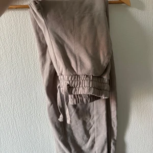 Beige mjukisbyxor från 157, strl S - Säljer ett par beige mjukisbyxor från 157 i storlek S. Byxorna har en bred resår med snörning i midjan och en stor ficka framtill. Mjukt material som är skönt mot huden och perfekt för chill dagar. Färgen är neutral och lätt att matcha med hoodies eller t-shirts.