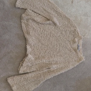 Beige stickad tröja från Zara - Mysig beige stickad tröja från Zara i storlek S. Tröjan har en fluffig och grovstickad struktur med långa ärmar och avslappnad passform. Perfekt för lager-på-lager och chill dagar. Superenkel att styla med jeans eller kjol.