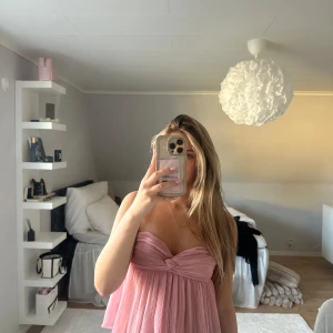 Rosa axelbandslös topp från Zara - Supersöt rosa topp från Zara med twistad detalj vid bysten. Lätt och flowy. Perfekt som en sommartopp eller till fest! Säljer då den tyvärr inte kommer till användning.