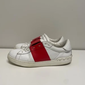Valentino Open Sneakers - Vita opens med röd rem. Fint skick men små defekter finns. Bara skor tillkommer.