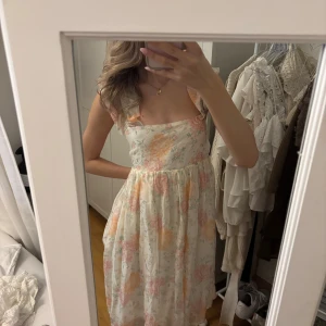 Blommig klänning  - Blommig klänning med knytning i bak från Hm. Den är en storlek m men pga man kan knyta den i bak så passar den mig som är en xs. Alltså passar den om man är mellan storlekarna xs/s/m💕 Den kommer till precis över knäna på mig.