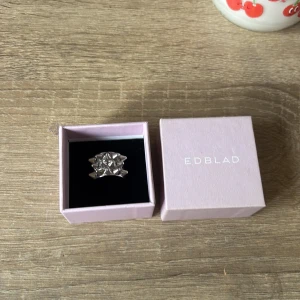 Silvrig statementring från Edblad - Cool och chunky ring från Edblad i blankt silverfärgat metall. Ringen har ett unikt geometriskt mönster med upphöjda spetsar som ger en edgy vibe. Perfekt för dig som gillar att sticka ut med dina accessoarer. Levereras i original ask.