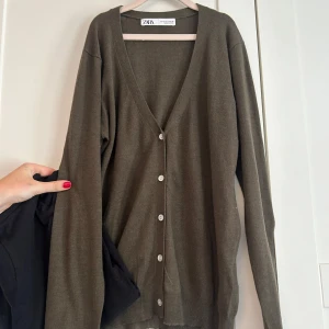 Grön kofta från Zara med knappar - Grön kofta från Zara i storlek S. Koftan har v-ringning, långa ärmar och stängs med vita knappar framtill. Den är tunn och mjuk 