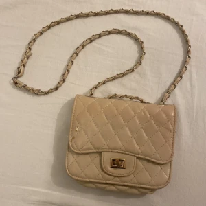 Beige väska med kedja - Snygg beige väska. Använt flertal gånger. Bra skick. Små defekter på väskan (se bilder).