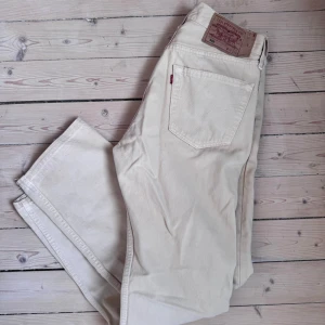 Levi's 501 vita jeans W32 L30 - Säljer ett par klassiska Levi's 501 jeans i vit färg. De har rak passform, fem fickor och knappgylf. Jeansen är tillverkade i bomull och har den ikoniska läderpatchen bak i midjan. Perfekta för en clean och stilren look. Något små i storleken så skulle säga mer 30x30