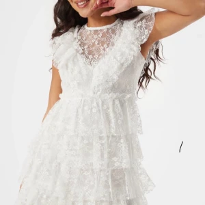 Vit spetsklänning från Bubbleroom - Superfin vit kortklänning från Bubbleroom med flera lager volanger och spetsdetaljer. Klänningen har korta ärmar, rund hals och v-ringad omlottkänsla framtill. Skulle använda till studenten men kom inte till användning! Spänningen baktill har gått upp men väldigt enkelt att bara sy dit igen.