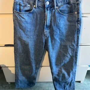 Blå relaxed tapered jeans från &Denim - Säljer ett par blå jeans från &Denim med relaxed fit och avsmalnande ben. Klassisk femficksmodell med resår i midjan för extra komfort. Perfekta om du gillar en lite lösare stil men ändå vill ha en snygg siluett.