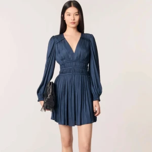 Mörkblå kortklänning från Maje - Supersnygg mörkblå kortklänning från Maje i glansigt material med v-ringning, långa ärmar och markerad midja. Använd max 2 gånger. Skriv vid eventuella frågor❤️