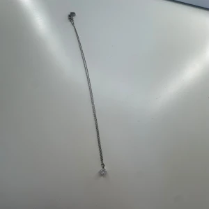 Silverhalsband med glittrig sten - Snyggt och stilrent halsband i silverfärg med en tunn kedja och en rund, glittrande sten som hänger som berlock. Perfekt för dig som gillar minimalistiska smycken med lite extra bling. Passar till alla dina favoritoutfits och ger en elegant touch.