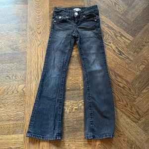 Svarta bootcut jeans Gina Tricot 134 - Snygga svarta jeans från Gina Tricot i storlek 134. Modellen har bootcut-ben och klassisk femficksdesign. Jeansen är tillverkade i ett mjukt denimtyg.