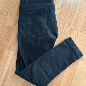 Svarta nudie jeans - Säjler ett par stilrena svarta nudie jeans som har en slim passform. Strolek: 32/30. Finns inga defekter och de är i toppskick men tveka inte att fråga vid funderingar.