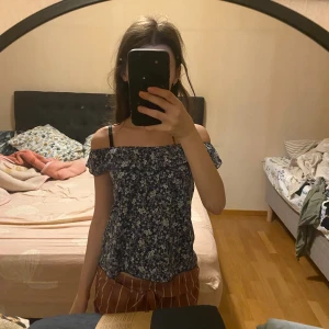 Blommig offshoulder topp  - Söt offshoulder topp med blommigt mönster i blått och vitt. Toppen har korta ärmar och en luftig passform.