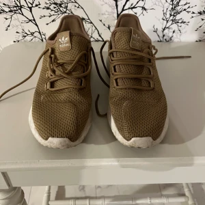 Adidas sneakers i beige mesh - Säljer ett par snygga Adidas sneakers i beige med vit sula. Skorna har en rund tå, snörning och är tillverkade i ventilerande syntetmesh. Perfekt för dig som gillar stilrena och bekväma sneakers med klassisk Adidas-logga på plösen och hälen.