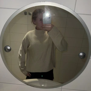 Beige stickad polotröja från Uniqlo - Mysig beige stickad polotröja från Uniqlo i storlek S. Tröjan har en hög ribbad krage, långa ärmar och breda ribbade muddar vid ärmslut och nederkant. Perfekt för lager-på-lager under kyliga dagar.