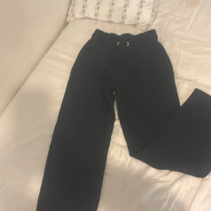 Svarta mjukisbyxor från lager 157 i strl XS - Svarta mjukisbyxor från lager 157  i storlek XS. Byxorna har elastisk midja med snörning, två fickor fram och två bak. Materialet är mjukt och skönt, perfekt för chill dagar. Passformen är loose och modellen är rak med normal längd.