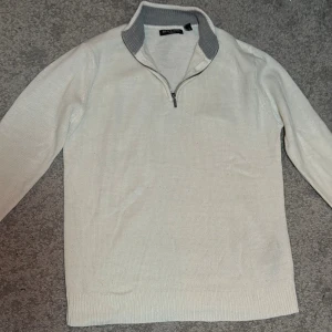 Vit stickad tröja med half zip - Snygg vit stickad tröja från Brave Soul i storlek S med grå ribbad krage och half zip-dragkedja. Tröjan har lång ärm och en klassisk passform, perfekt för lager-på-lager. Enkel och stilren design som funkar till många outfits.