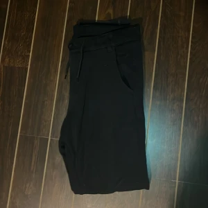 Svarta byxor från KappAhl med snörning - Svarta byxor från KappAhl med elastisk midja och snörning. Byxorna har raka ben, sidofickor och en bakficka. Materialet känns mjukt och stretchigt, perfekt för en chill och stilren look.