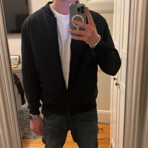 Marinblå cardigan från Dustin - Säljer en riktigt fet cardigan från Dustin i storlek M. Materialet är slätt och känns lätt, perfekt för dig som gillar en clean look. Passar många feta outfits 