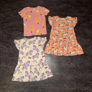 Unicorn klänning med volang från Lindex - Superfin kortklänning från Lindex med gulligt unicorn-mönster i lila och regnbågsfärger på ljus botten. Klänningen har volang nertill, rund hals och korta ärmar. Perfekt för dig som älskar magiska prints och färg! Plaggen är i 98/104, alla från lindex.  Finns någon dov fläck på nått plagg annars är alla plagg i nyskick!