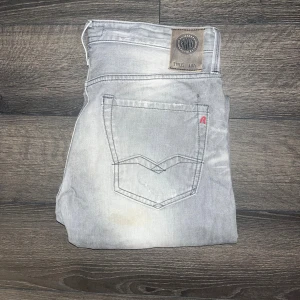 Replay Waitom jeans  - Snygga ljusgrå replay Waitom. Se defekt på sista bilden ! Jag har ej provat tvätta bort fläckarna så möjligt att de kan försvinna och annars syns de inte särskilt mycket som ni ser på de andra bilderna :) midja 44cm, längd 104cm storleks lappen med L storleken är borta men jag bedömer den till L32 men utgå från måtten! JAG SKICKAR EJ FLER BILDER NÄR JAG BÄR JEANSEN! för storleksguide hänvisar jag till måtten och för bättre inblick i passformen rekommenderar jag att googla på modellnamnet :) s3