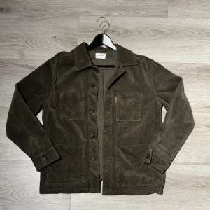Studio total overshirt - Säljer en mörkgrön overshirt från Studio total i mjuk manchester. Jackan har klassisk krage, stora frontfickor och knäppning med svarta knappar. Perfekt nu till hösten och vinten när man kör lager på lager.